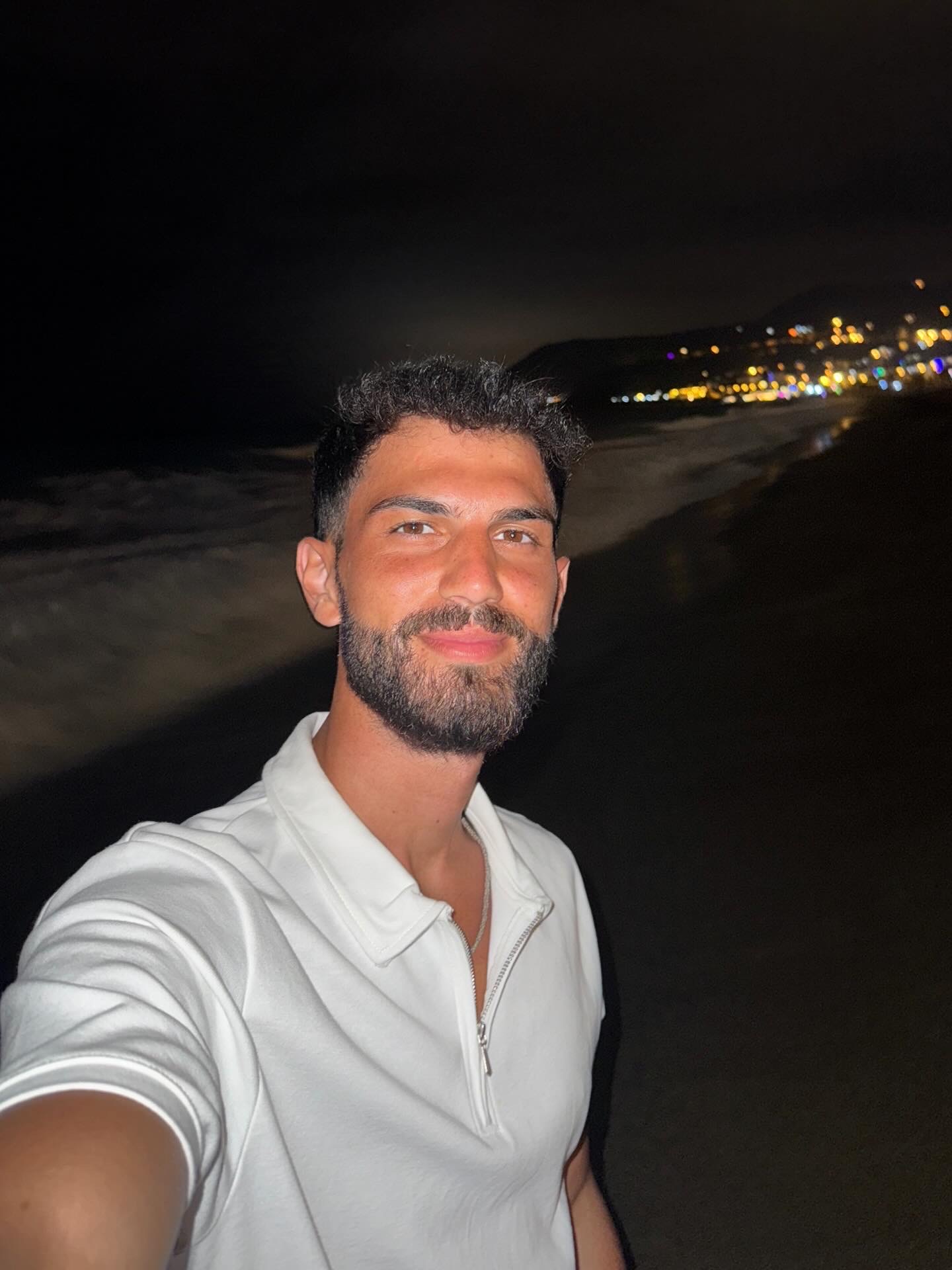 Ali Tara in a white polo at the beach at night